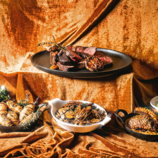 An assortment of steak and side dishes against a gold velvet backdrop at Aera in Toronto