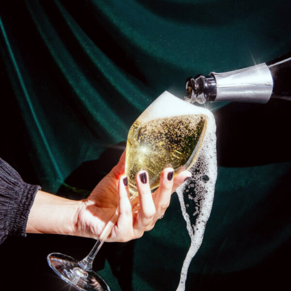 Hand holding glass of Champagne overflowing at Aera Restaurant Toronto