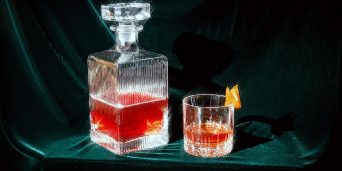 glass decanter and cocktail glass against green velvet backdrop at Aera Restaurant